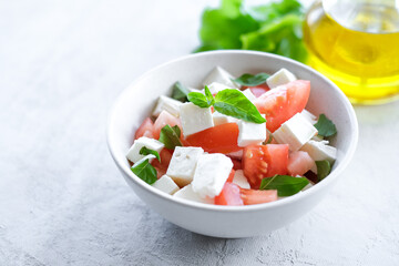 Italian caprese salad with sliced tomatoes, mozzarella, basil, olive oil on a light background. 