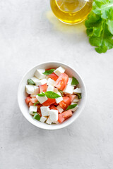 Italian caprese salad with sliced tomatoes, mozzarella, basil, olive oil on a light background. 