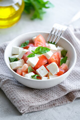 Italian caprese salad with sliced tomatoes, mozzarella, basil, olive oil on a light background. 