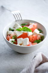 Italian caprese salad with sliced tomatoes, mozzarella, basil, olive oil on a light background. 