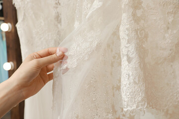 Young woman choosing wedding dress in salon, closeup