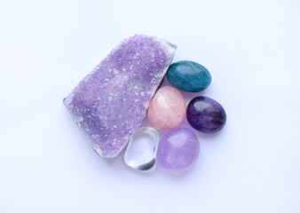Tumbled gems and crystals of various colors. Amethystdruze, rose quartz, apatite, rock crystal on white background.