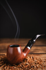 Smoking pipe with tobacco on wooden table