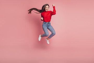 Young jumping high air woman celebrate win on pink background