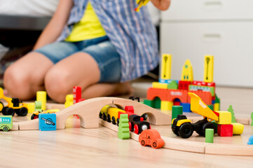 Boy plays with wooden toys. train rails, wooden block buildings.