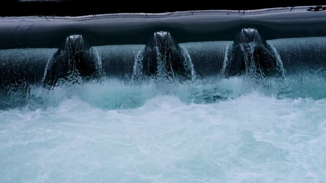 streams of water seethe in powerful waterfall, historic dam on Reuss river flowing from Lake Lucerne in switzerland, top view of stream bubbles, rippled liquid textured surface background