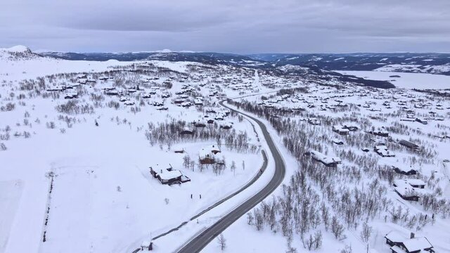 Panorama over Beitost&oslash;len village and ski resort with cozy log cabins on a cloudy winters day.