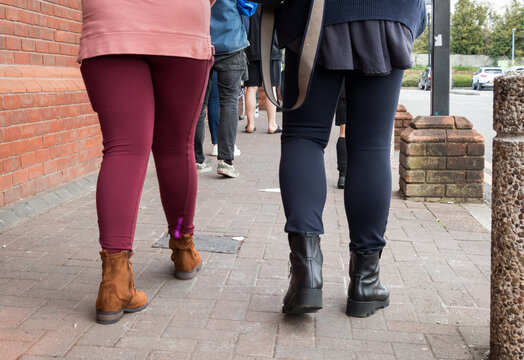 Legs And Feet Of People Waiting In Line To Enter A Shop During The Covid-19 Pandemic