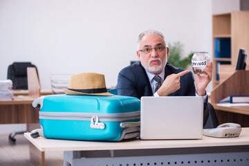 Old male employee preparing for travel in the office