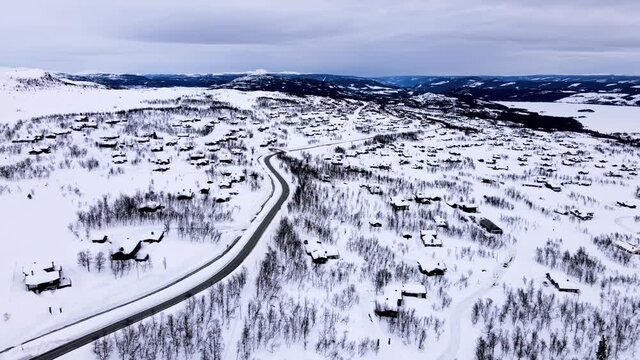 Panorama over Beitost&oslash;len village and ski resort with cozy log cabins on a cloudy winters day.