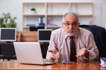 Old male employee in gambling concept at workplace