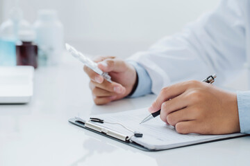 Doctor hold in one hand a blister with pills and write prescription to patient at work table. Panacea and life save prescribing treatment legal drug store concept.