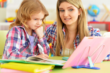 Mother and daughter doing homework together  in room