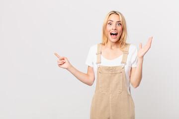 young blonde woman feeling happy and astonished at something unbelievable