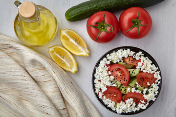 Bowl with chopped tomatoes and cucumbers, cottage cheese and black cumin seeds