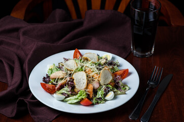 Healthy green organic caesar salad with cheese and croutons. A plate with salad on a wooden table in a restaurant