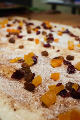 A pastry chef spreads candied fruit, raisins and chocolate pieces on puff pastry. Making dough curls. The job of a pastry chef. Making desserts