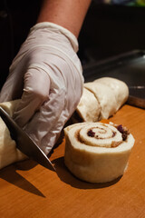A pastry chef spreads candied fruit, raisins and chocolate pieces on puff pastry. Making dough curls. The job of a pastry chef. Making desserts
