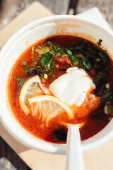 Close-up of a hodgepodge in a disposable paper cup. The concept of traditional food and foreign cuisine. Safe eco-friendly disposable tableware.