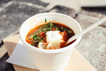 Close-up of a hodgepodge in a disposable paper cup. The concept of traditional food and foreign cuisine. Safe eco-friendly disposable tableware.