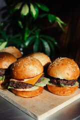 Mini burger on a stand close-up. Children fast food in a restaurant or cafe. Macro photo of burger ingredients with meat and vegetables. Eco burgers for children