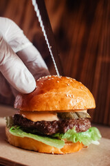 Mini burger on a stand close-up. Children fast food in a restaurant or cafe. Macro photo of burger ingredients with meat and vegetables. Eco burgers for children