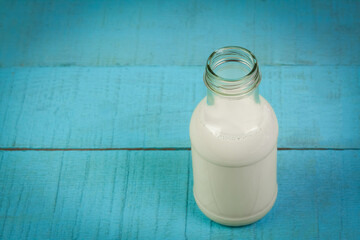 Milk in bottle on blue wooden table.
