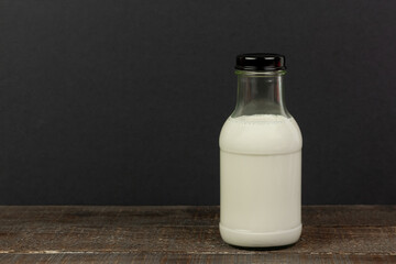 Milk in bottle on wooden table and black background.