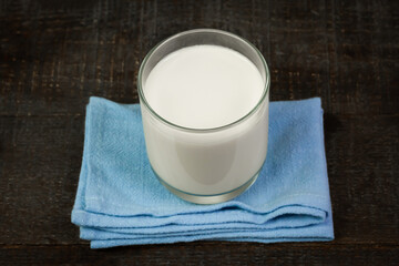 Milk in glass on rustic wooden table.