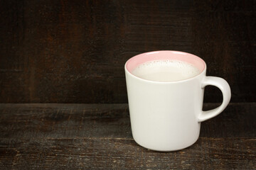 Milk in ceramic mug on wooden table. 