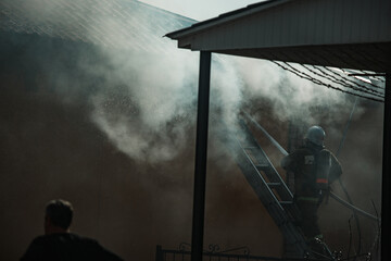 the fire destroys the building. the fire brigade pours water on the burning house. people are...