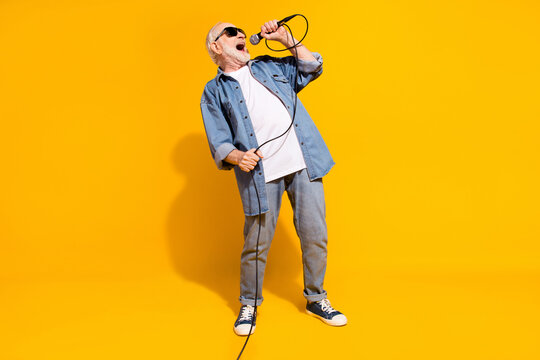 Full body portrait of excited positive man hand hold mic singing loud open mouth isolated on yellow color background