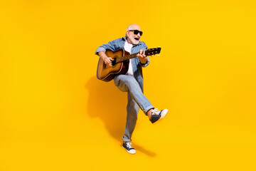 Full length photo of cool happy positive old man dance hold guitar wear sunglass isolated on yellow color background