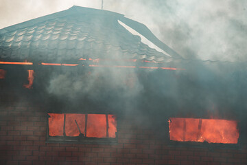 the fire destroys the building. the fire brigade pours water on the burning house. people are...