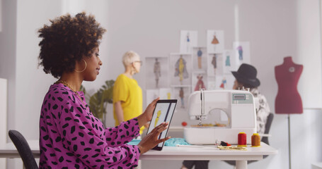 Female fashion designer using digital tablet in creative office