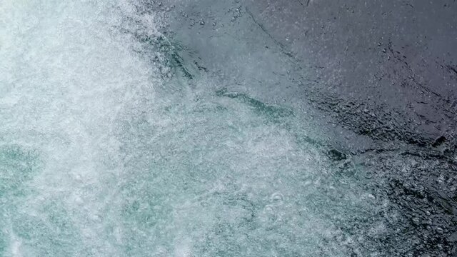 streams of water seethe in powerful waterfall, historic dam on Reuss river flowing from Lake Lucerne in switzerland, top view of stream bubbles, rippled liquid textured surface background