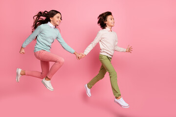 Fototapeta na wymiar Full length body size view of nice trendy cheerful kids jumping having fun walking isolated over pink pastel color background