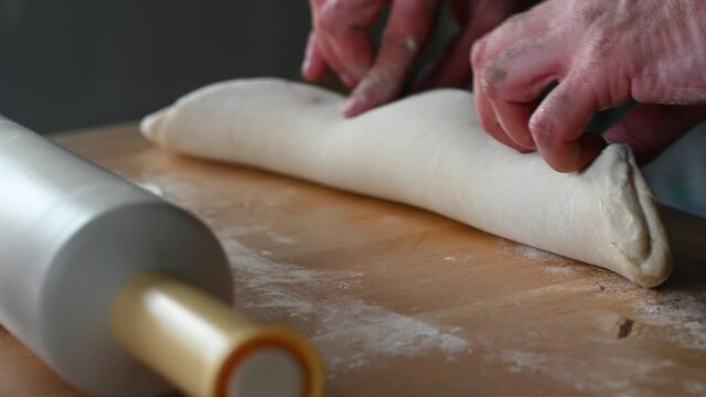 a rolling pin lies on the table a man prepares dough for chebureks makes balls of dough cuts the dough with a knife concept of homemade food. High quality 4k footage