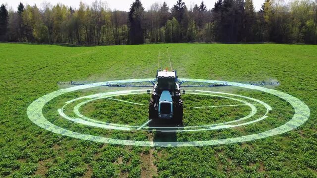Aerial view of autonomous self-driving tractor with autopilot spraying mineral, nitrogen fertilizer or pesticides on an agricultural field. The agricultural vehicle uses sensors and a GPS signal.