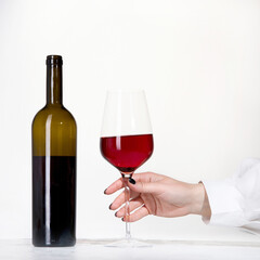 Young woman holding glass of rose wine on white background. Hand with black polish.
