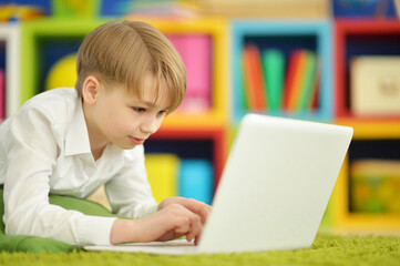 exited boy using laptop while lying on floor