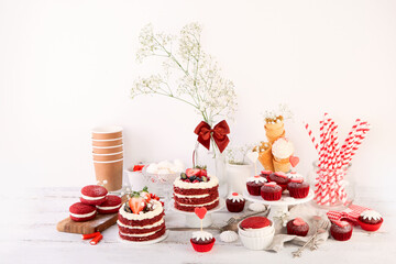 Delicious cake and cupcakes in red on white background. Table setting for celebration.