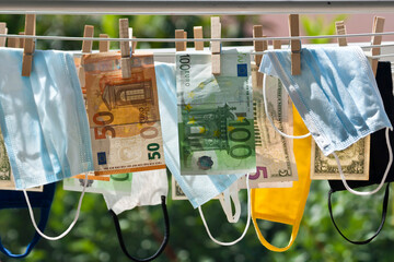 Money laundering concept: Face masks hanging on clotheslines near dollar and euro bills