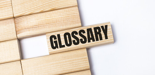 On a light background, wooden blocks with the text GLOSSARY. Close-up top view.