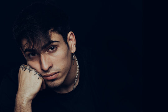 Young man with tattoos and earrings with a pensive expression