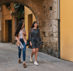 Obraz na płótnie Canvas Two tourist girls walking through the city streets on vacation