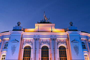 The main building of Warsaw University of Technology at dusk lit by colorful lights. Warsaw, Poland.