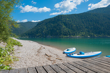beautiful beach lake achensee with standup paddling boards at the shore, austrian landscape