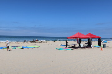 People Enjoying a San Diego, California, Beach with Surfboards ready to Be Used By Tourists with the Ocean in the Background