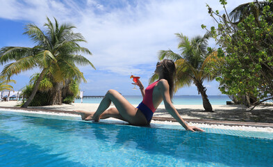 girl in bikini with cocktail in tropical pool